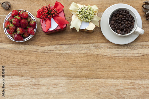above copy space, strawberry in cup,gift boxes and coffee beans in cup on wooden desk.