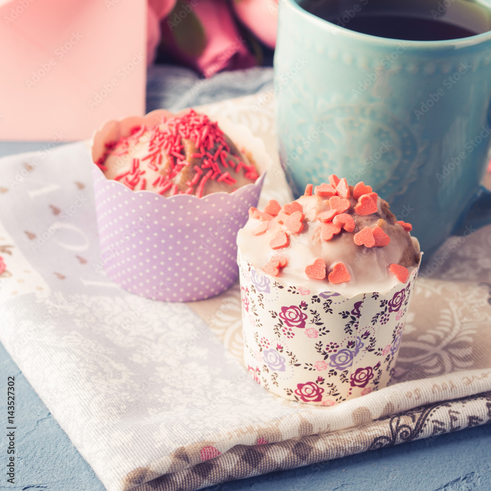 Mother's day Valentine concept muffins with hearts sprinkles and cup of tea on napkin. Flowers Mother's day Valentine concept muffins with hearts sprinkles and cup of tea on napkin. Flowers
