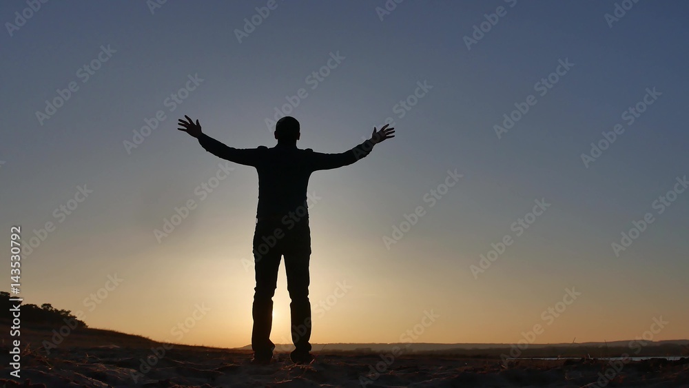 freedom. Man stands on a cliff sunset silhouette hand in lifestyle the sides