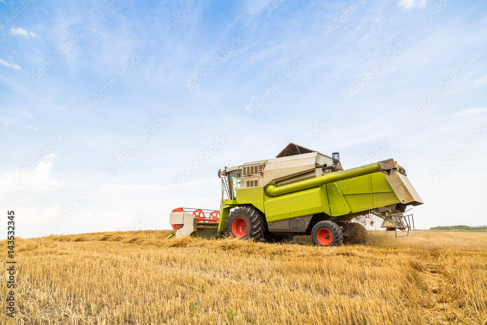 Combine harvester in action on wheat field. Harvesting is the process of gathering a ripe crop from the fields. Combine harvester in action on wheat field. Harvesting is the process of gathering a ripe crop from the fields.