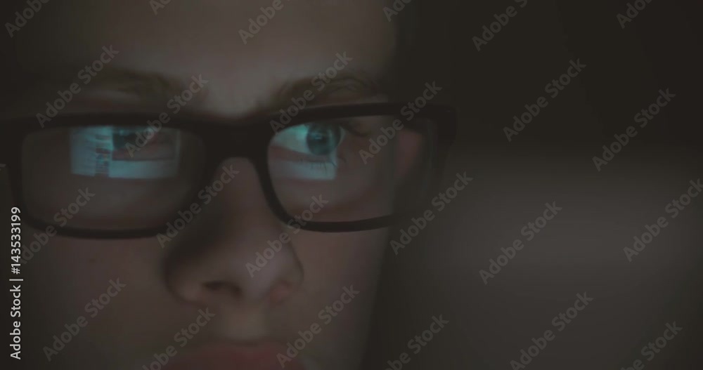 boy working at a computer in a dark room, surfing the Internet, close-up