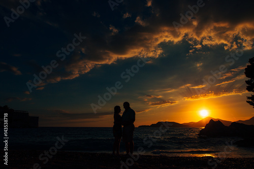 Silhouette of a newlywed couple at the sea at sunset. Wedding in Montenegro. Silhouettes of the couple, the bride and groom.