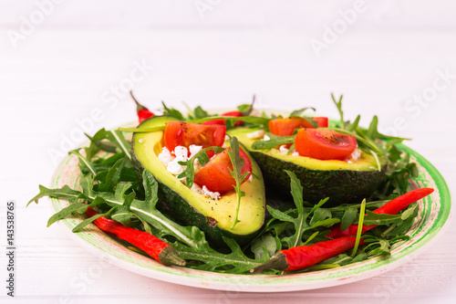 Avocado stuffed with feta cheese, arugula and tomatoes