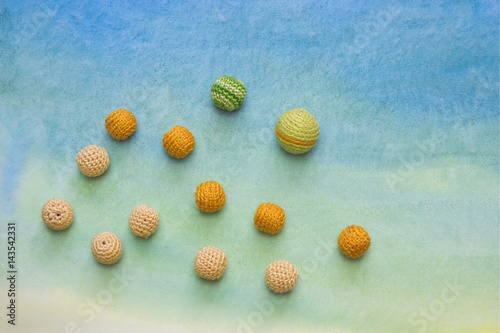 Small crochet beads on the watercolor background. Handmade creative craft backdrop
