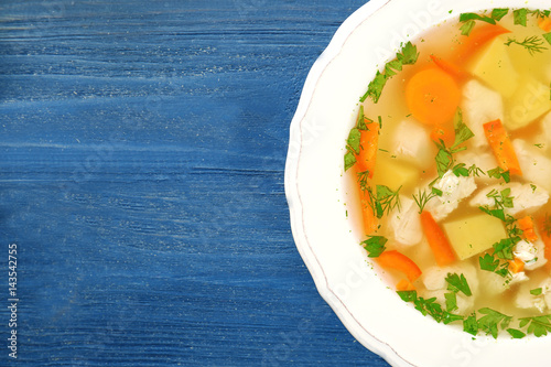 Plate with chicken soup on wooden table