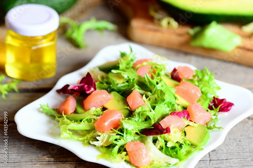 Salmon, avocado and lettuce mix salad. Home salad with slices of smoked salmon, fresh avocado and lettuce leaves mix on a plate. Delicious and healthy appetizer. Closeup