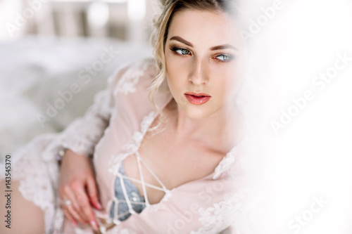 the bride in a Bathrobe to the bedroom window in the morning photo