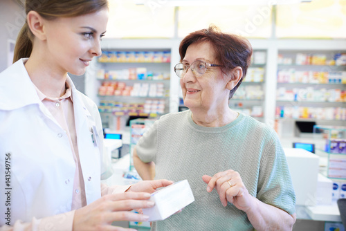 Female pharmacist assisting senior woman