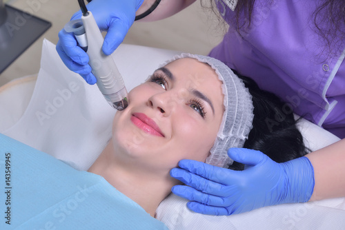 Young beautiful woman gets professional rejuvenation facial skin treatment in a professional beauty clinic