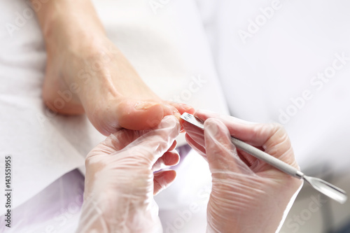 Pedicure, wycinanie skórek. Kosmetyczka wykonuje zabieg pedicure, czyści i obcina paznokcie u stóp