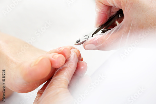 Pedicure. Kosmetyczka wycina cążkami skórki przy paznokciach i wykonuje profesjonalny pedicure.