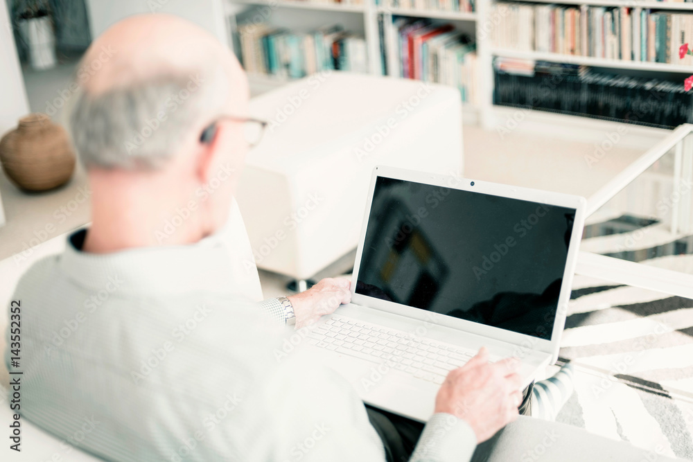 Man on couch with laptop at home. Over shoulder shot. Man on couch with laptop at home. Over shoulder shot.
