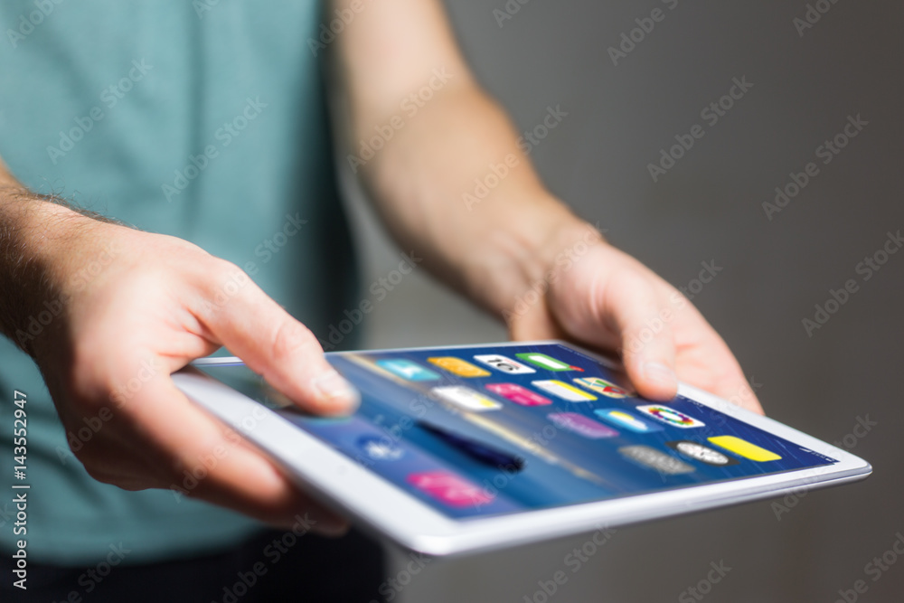 Hand holding black tablet with operating system screen