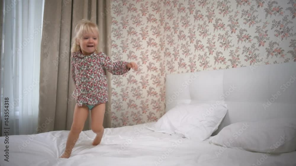 Adorable girl running in circles on the bed and smiling slow motion Adorable girl running in circles on the bed and smiling slow motion