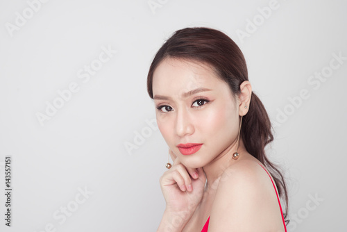 Portrait of stylish asian woman wearing red dress on grey background.