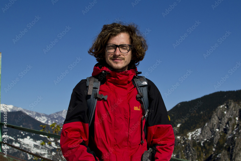 Young guy with glasses traveler, a backpacker traveling through Europe, up into the mountains, the Alps, to a height, the traveler in the mountains Young guy with glasses traveler, a backpacker traveling through Europe, up into the mountains, the Alps, to a height, the traveler in the mountains