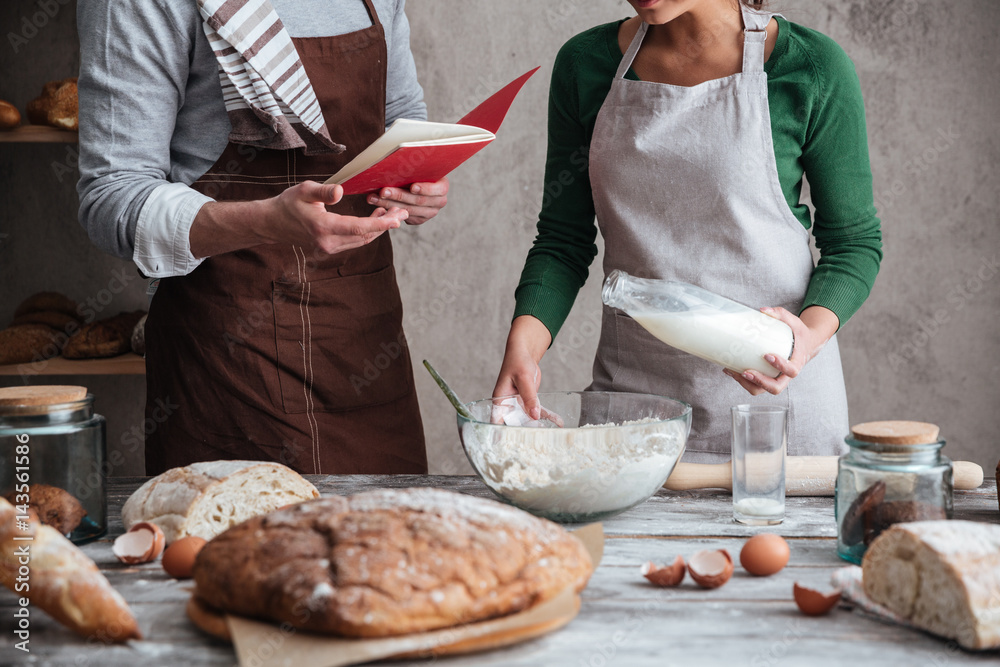 Cropped image of loving couple bakers cooking. Cropped image of loving couple bakers cooking.