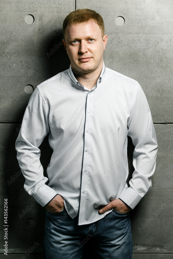 Successful man on the background of concrete walls in a shirt and pants Successful man on the background of concrete walls in a shirt and pants