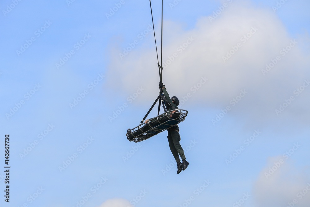Soldier rescue emergency by army helicopter with rope on blue sky Soldier rescue emergency by army helicopter with rope on blue sky
