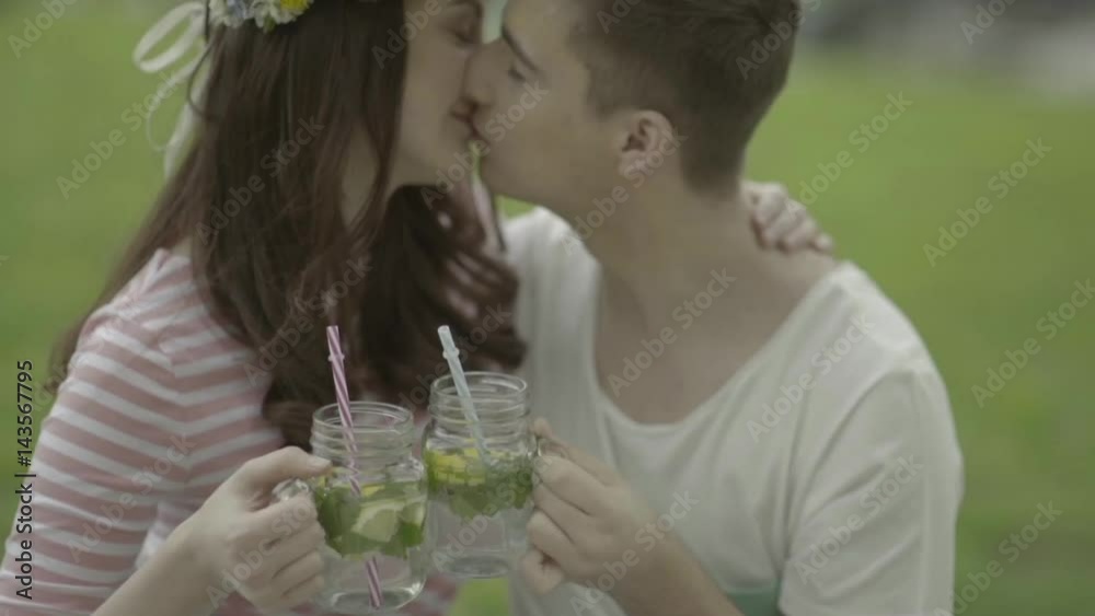 Verliebtes Paar küsst sich mit Limonade beim Picknick im Garten