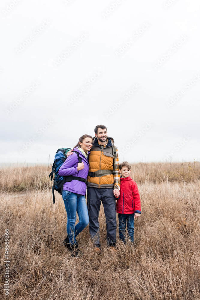 Happy family with backpacks standing in grass Happy family with backpacks standing in grass