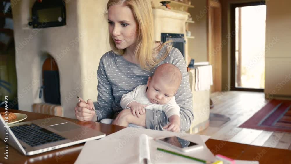 Beautiful mother with son in the arms, working on laptop Beautiful mother with son in the arms, working on laptop
