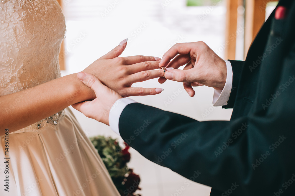 Loving couple holding hands with rings against wedding dress