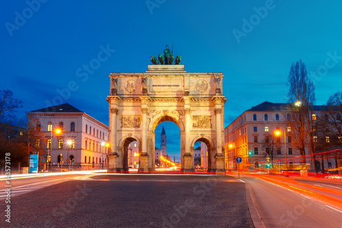 The Siegestor or Victory Gate, triumphal arch crowned with a statue of Bavaria with a lion-quadriga, at night in Munich, Germany photo