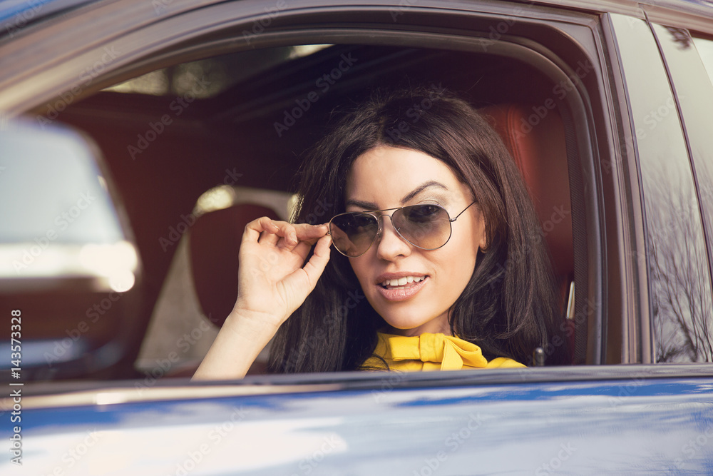 Attractive woman driver with sunglasses sitting inside her car