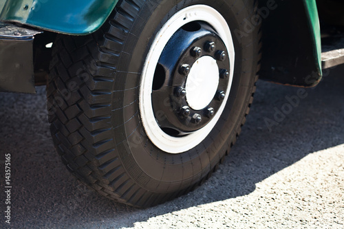 Retro truck wheel, asphalt background. Macro view. soft focus. Old style car part © besjunior