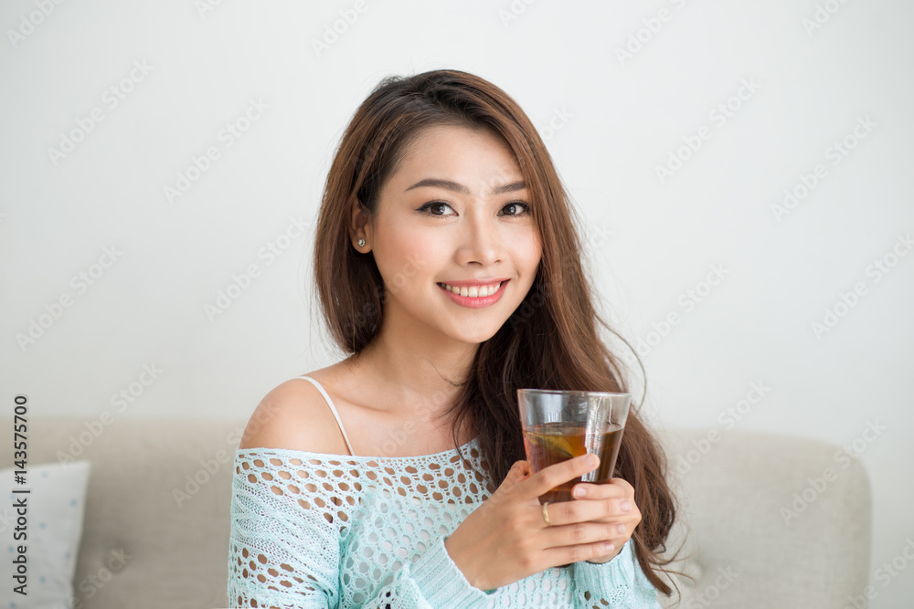 Beautiful young asian woman drinking her morning tea over a breakfast at home. Beautiful young asian woman drinking her morning tea over a breakfast at home.