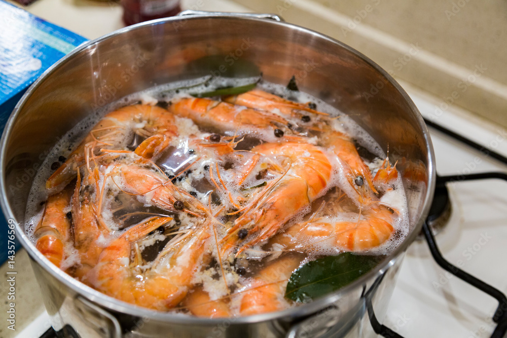 Giant tiger shrimps with heads are cooked with a laurel leaf in a saucepan on a gas stove Giant tiger shrimps with heads are cooked with a laurel leaf in a saucepan on a gas stove