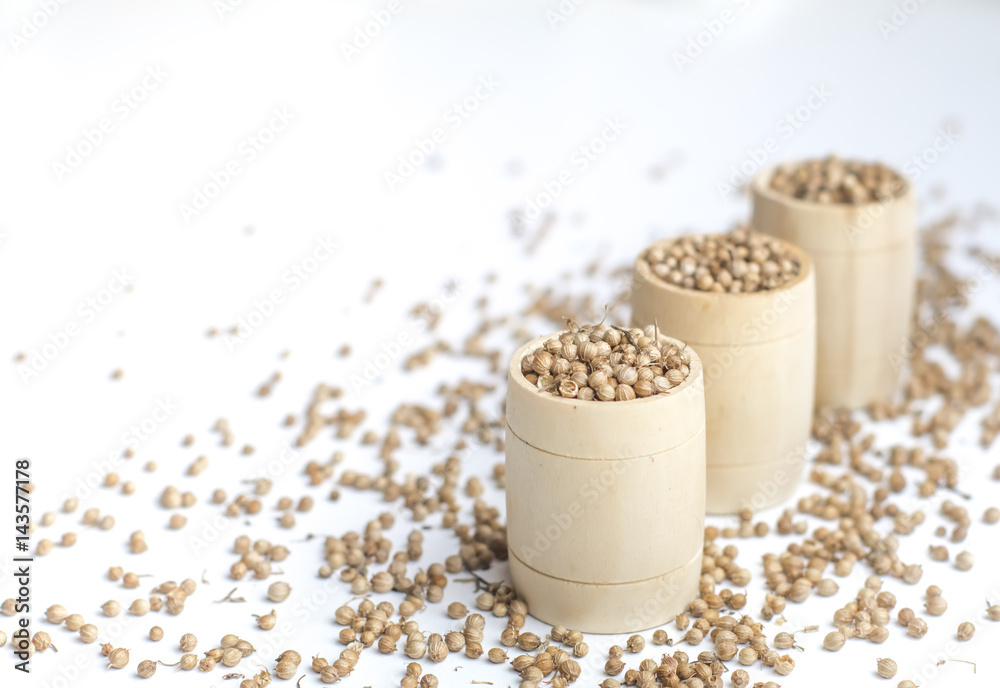 Organic Dried coriander seeds (Coriandrum sativum) in a wooden jar, selective focus, on white background Organic Dried coriander seeds (Coriandrum sativum) in a wooden jar, selective focus, on white background