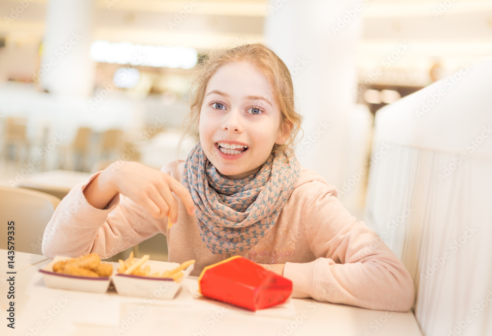 Child girl (kid) eating dinner in a fast food restaurant Child girl (kid) eating dinner in a fast food restaurant