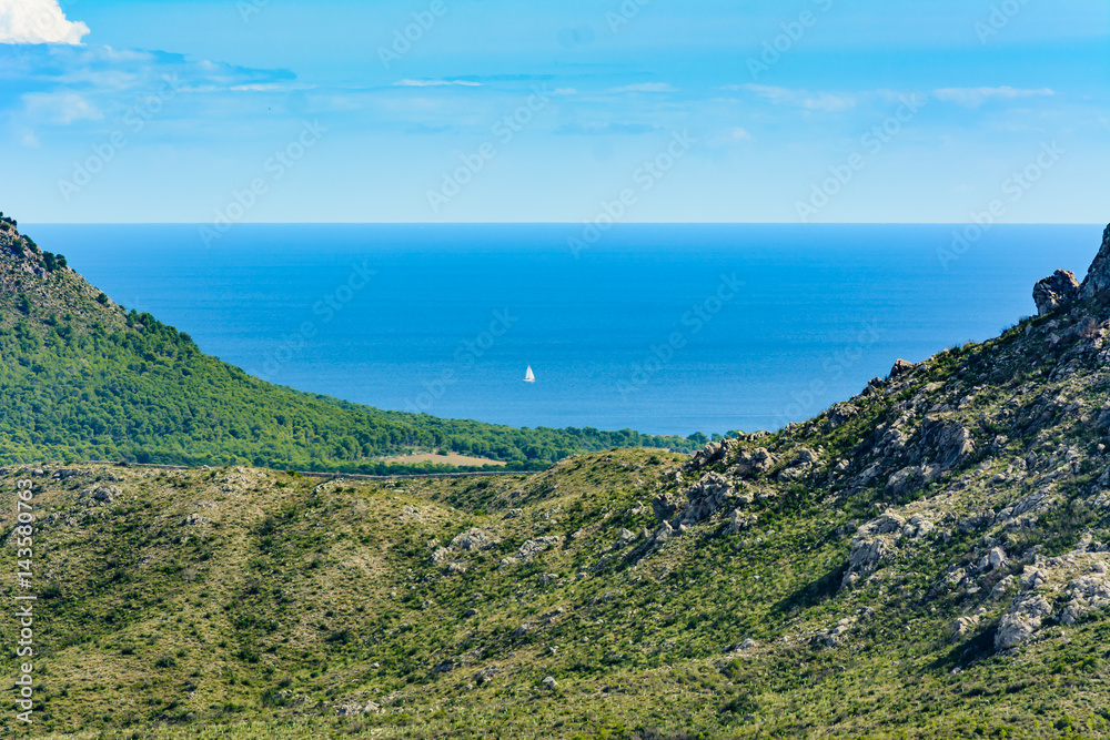 Sailboat / yacht in the middle of the sea flanked by mountains in the shape of U.