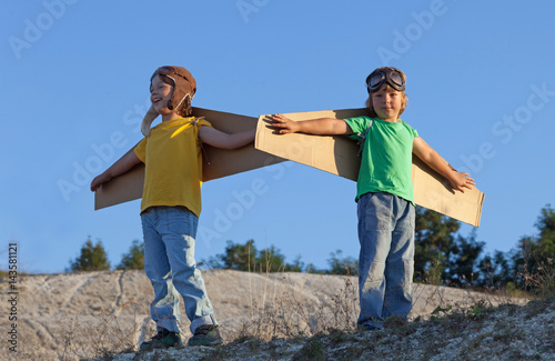Happy boy with cardboard boxes of wings against sky dream of flying