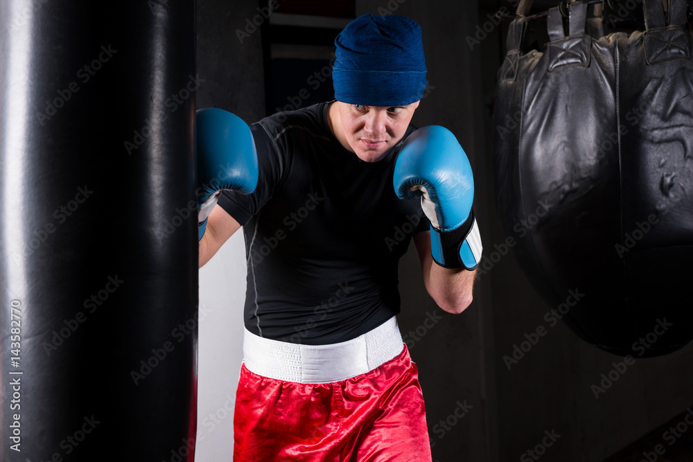 Sporty boxer in boxing gloves training with boxing punching bag