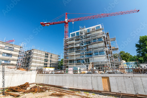 Baustelle mit Baukran und Fundament eines Neubaus und Wohnungen im Hintergrund photo