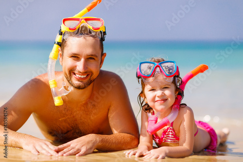 Happy family father and child wearing mask and laughing on beach