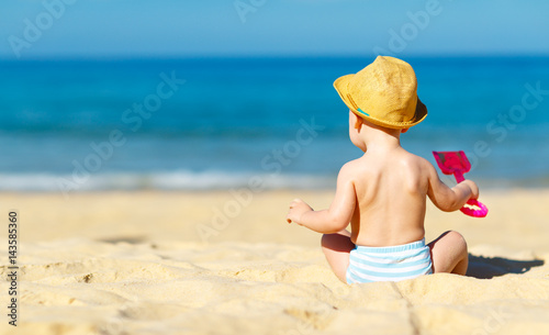 Canvas Print baby boy sit back with toys  on beach