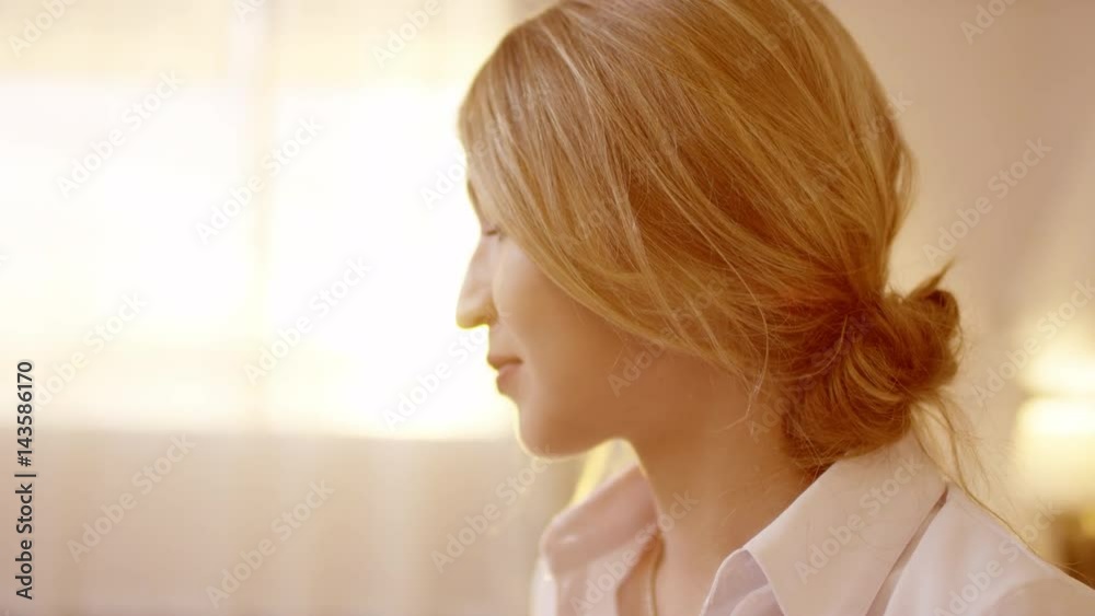 Young beautiful blonde woman turning head and smiling at camera