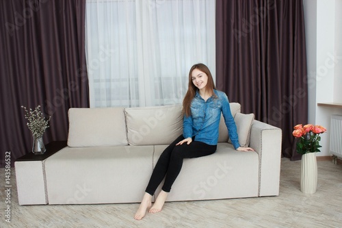 Portrait of happy young woman sitting on sofa © Saksoni