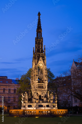 Kranner's fountain, Park of National Awakening, Prague, Czech Republic / Czechia - historical landmark made in style of gothic revival. Blue sky during twilight and lit building 