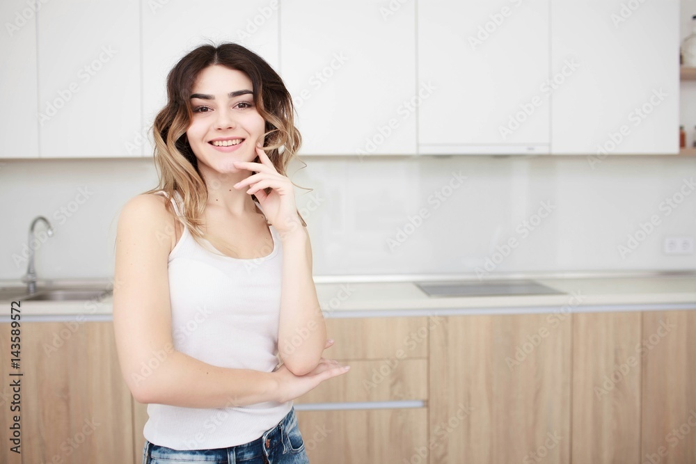 Pretty young woman standing in kitchen and smiling. Pretty young woman standing in kitchen and smiling.