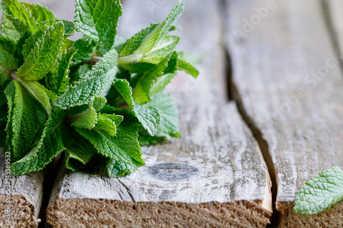 Close-up of a bunch of fresh green peppermint on an old wooden rustic table. Food and health care background.