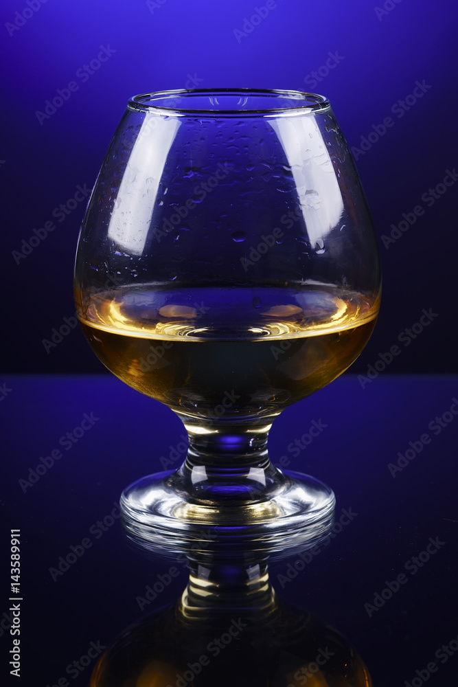 wineglass of cognac on a blue gradient background wineglass of cognac on a blue gradient background