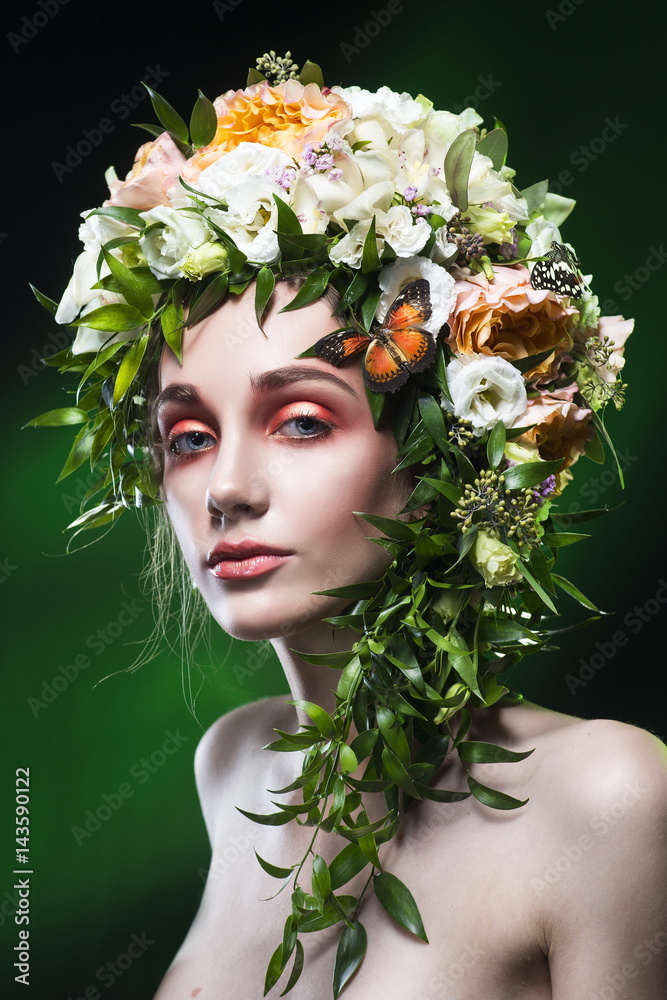 portrait of the young woman with hair decoration of hair from leaves, flowers and butterflies on a green gradient background