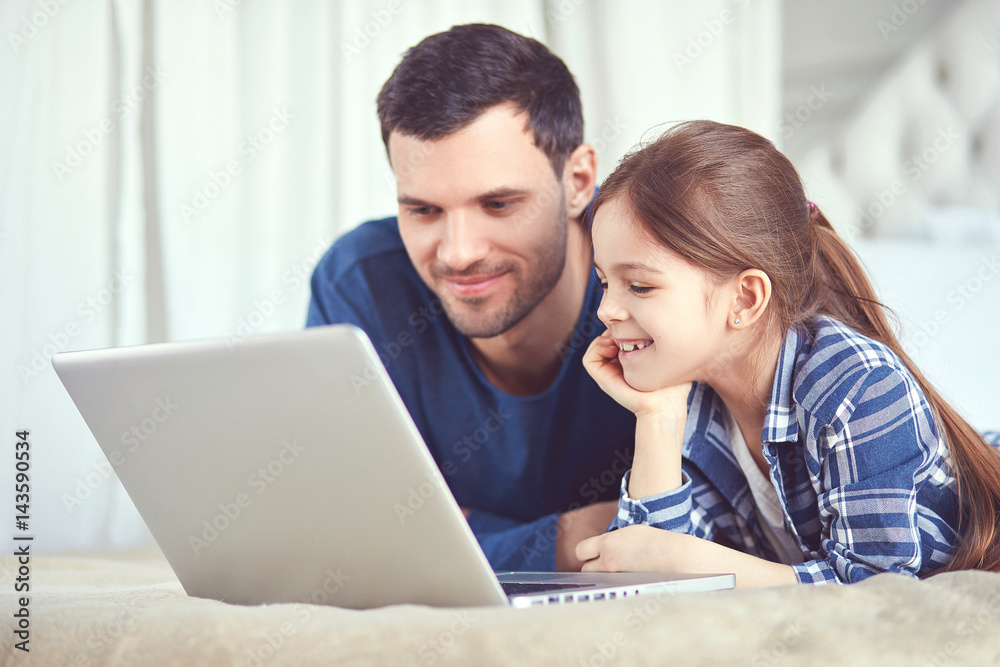 Father and his daughter are looking at the screen of their laptop Father and his daughter are looking at the screen of their laptop