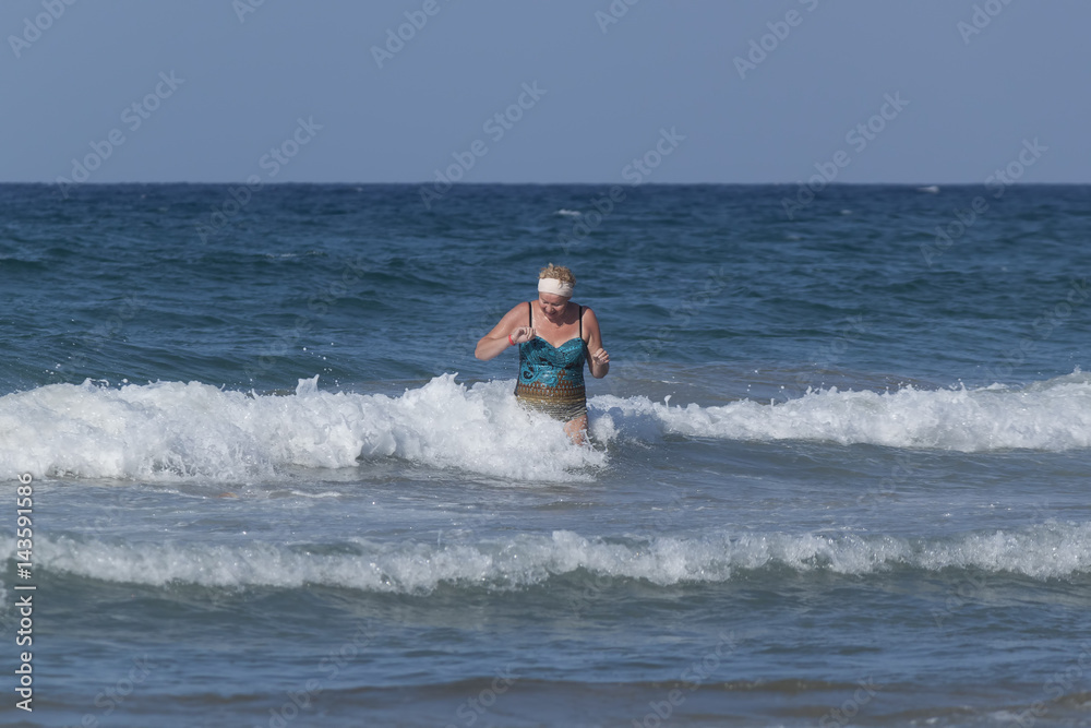 Middle-aged woman comes out of the sea Middle-aged woman comes out of the sea