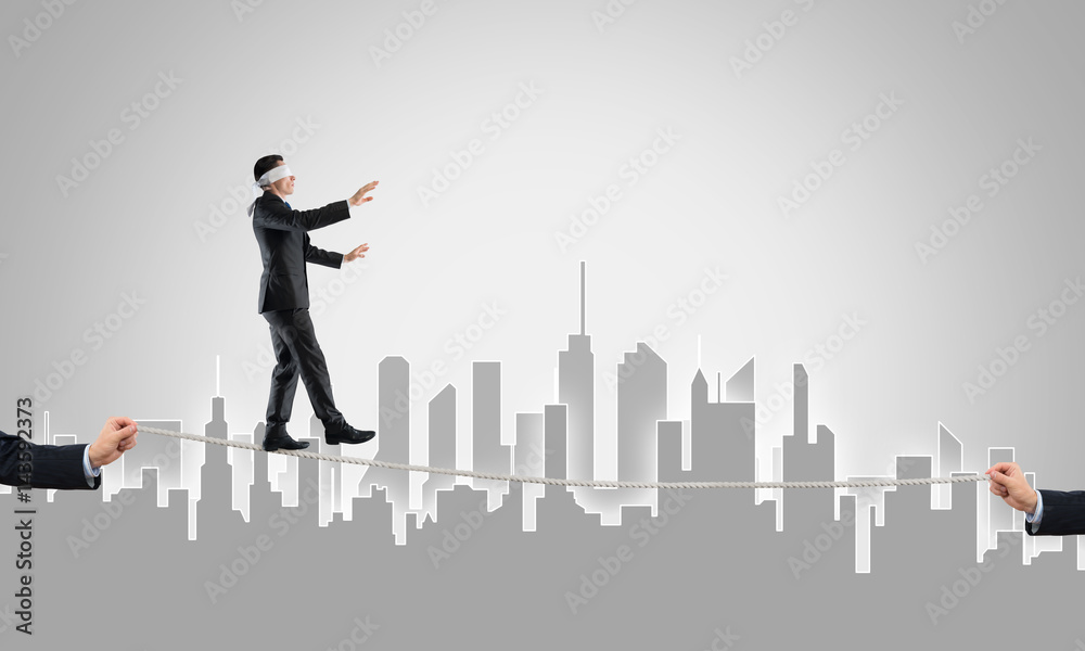 Business concept of risk support and assistance with man balancing on rope Business concept of risk support and assistance with man balancing on rope